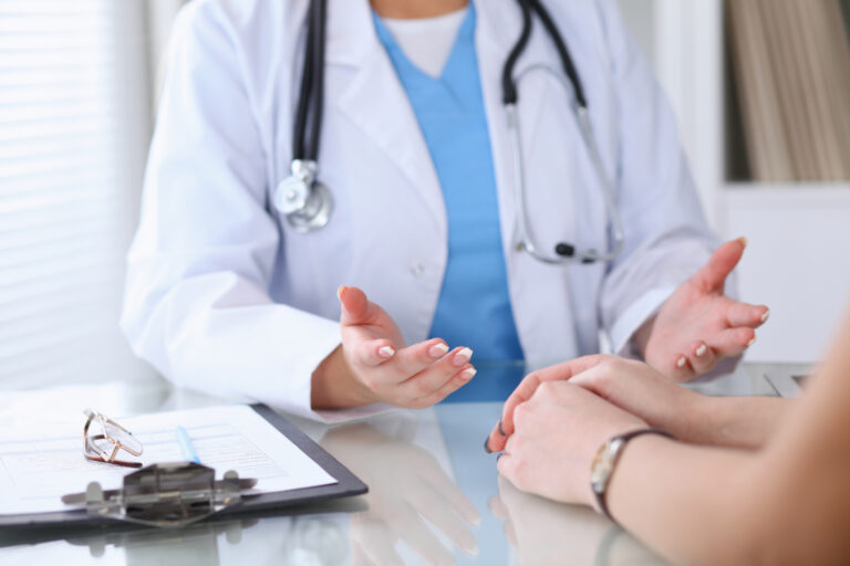 close up of a doctor and patient hands discussing something while sitting at the table